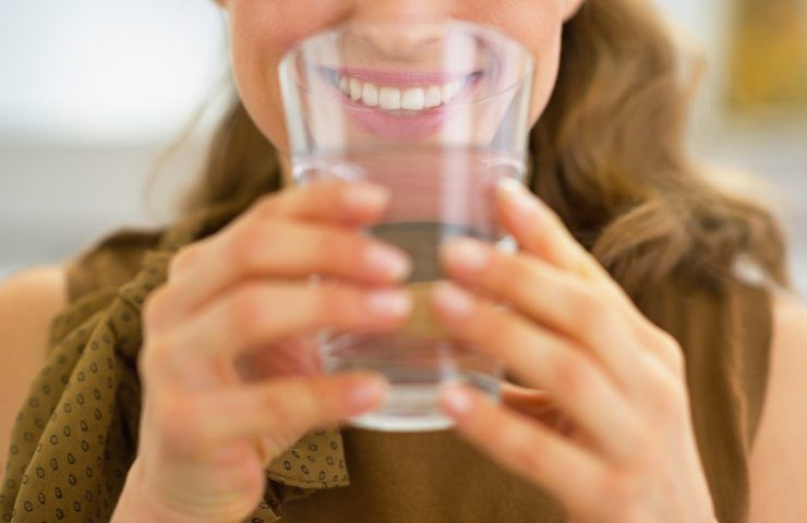 Una donna che beve da un bicchiere di acqua