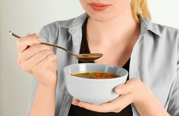 Una donna mangia una zuppa di legumi 