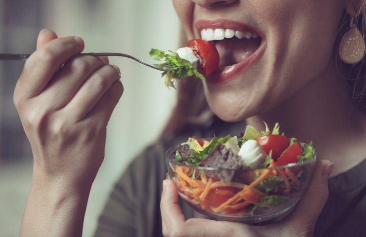 Una donna mentre mangia una insalata mista