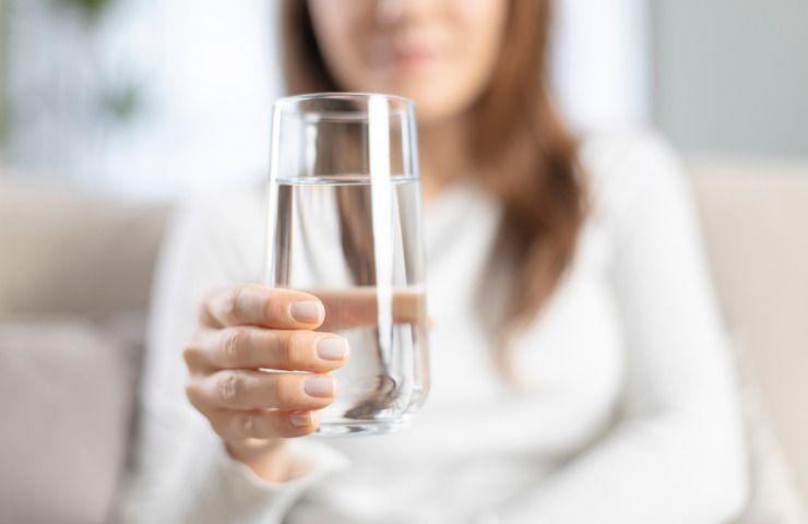 Una donna mentre regge un bicchiere di acqua