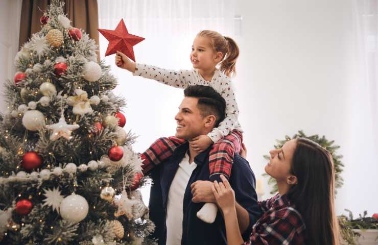 Una famiglia sistema il puntale sul proprio albero di Natale