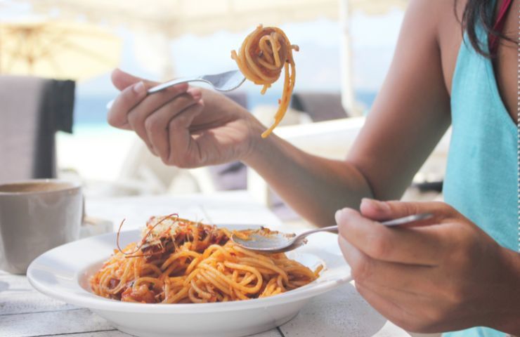 Una donna mentre mangia un piatto di pasta