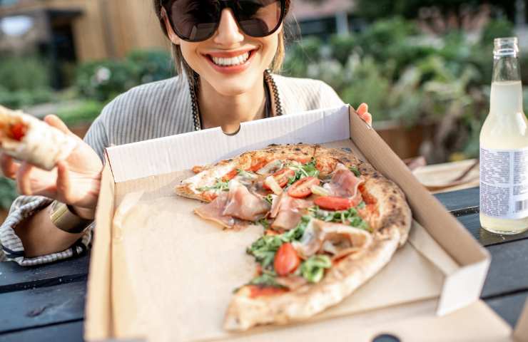 Una donna mentre mangia una pizza