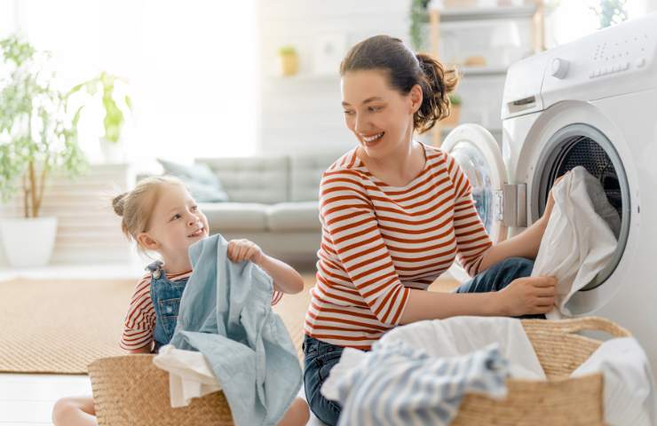Una donna ed una bambina mentre estraggono i panni dalla lavatrice