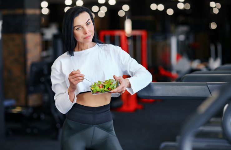 Una donna mangia in palestra prima di fare sport