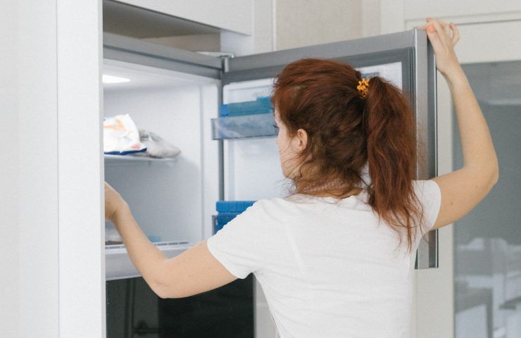 Una donna mentre mette qualcosa in un congelatore aperto