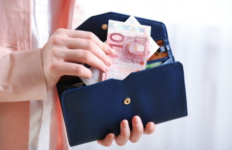 Una persona estrae delle banconote in euro da un borsellino