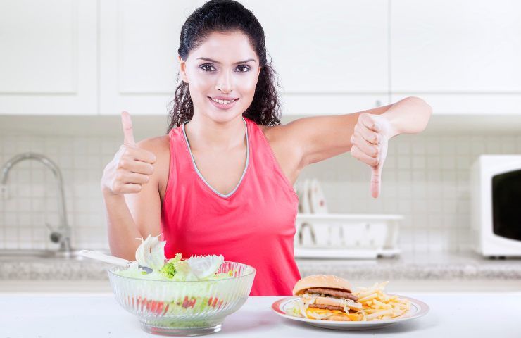 Una donna con del cibo sano ed altro non salutare