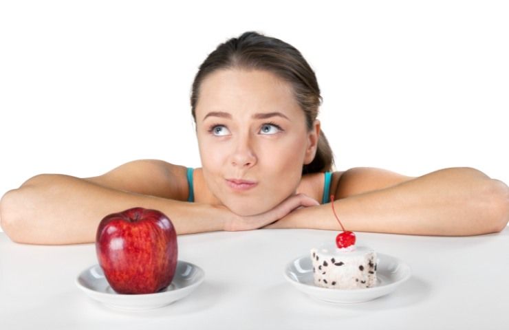 Una donna con una mela ed un dolce davanti