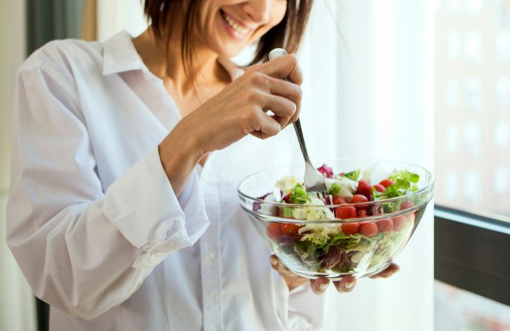 Una donna mentre pranza con alimenti sani e naturali