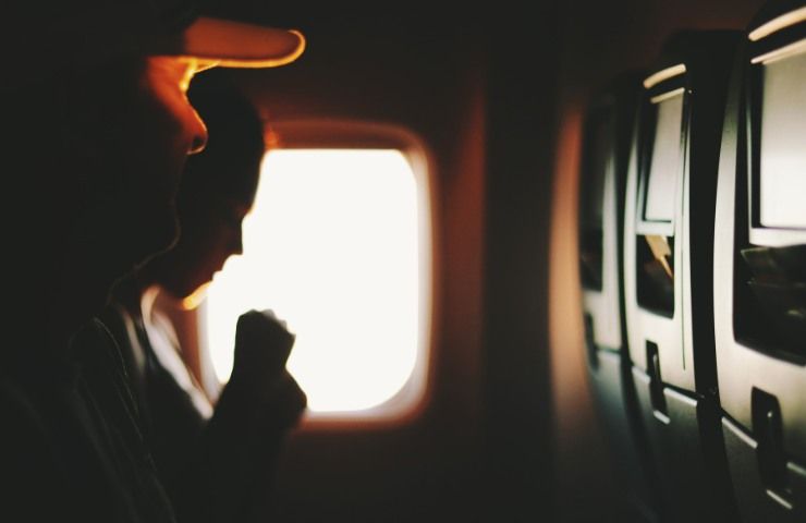 Una persona mentre tossisce a bordo di un aereo