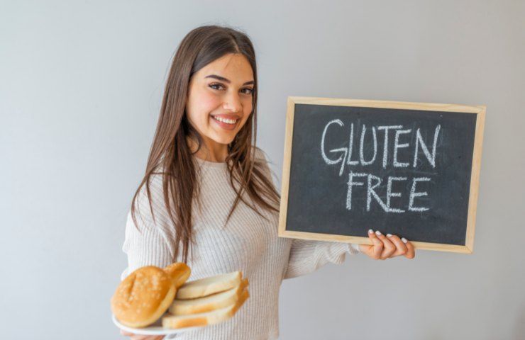 Una ragazza con una lavagna con su scritto Gluten Free