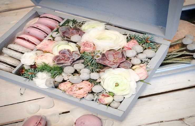 Una scatola riempita con fiori e dolciumi