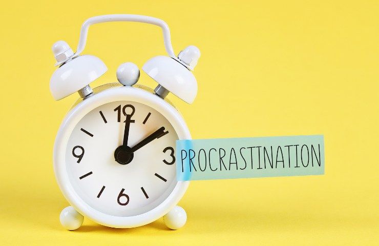Una sveglia e la parola Procrastinazione