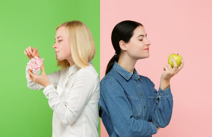 Due donne che mangiano rispettivamente un dolce ed una mela