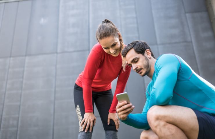 Un uomo ed una donna in forma consultano i risultati di una app per la salute