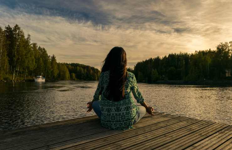 Una donna che medita su un lago