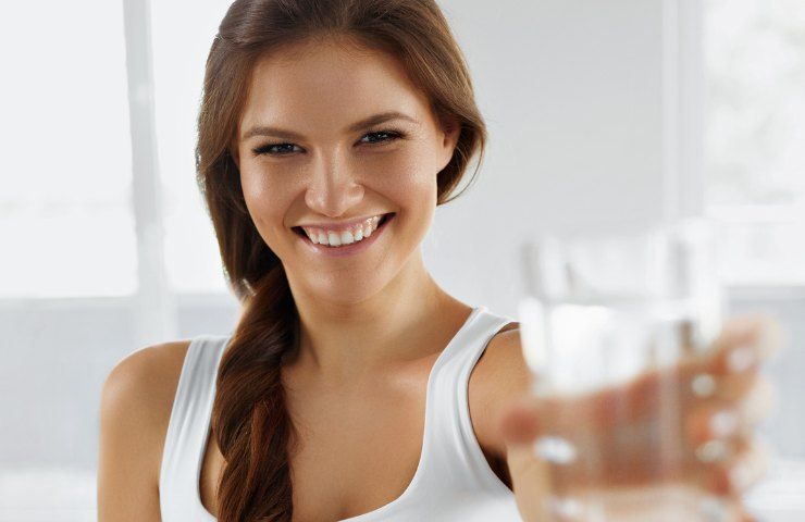 Una donna mentre porge un bicchiere di acqua