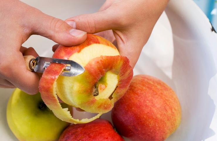 Una persona mentre sbuccia una mela
