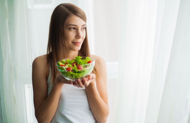 Una ragazza che mangia degli ortaggi freschi