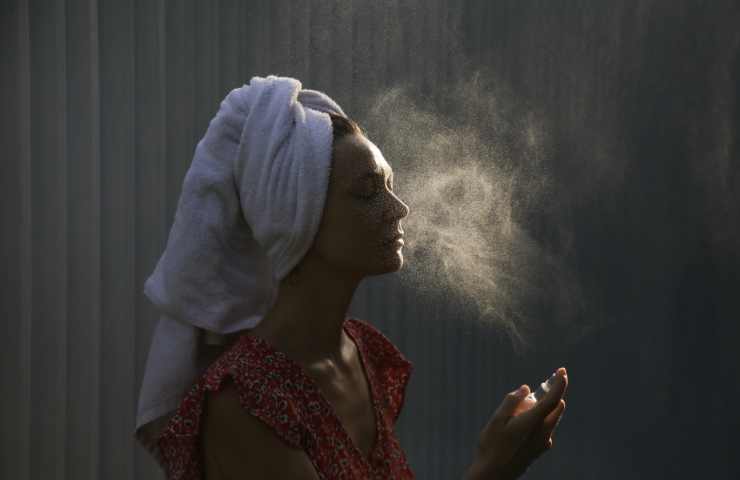 ragazza che nebulizza l'acido ialuronico sul viso