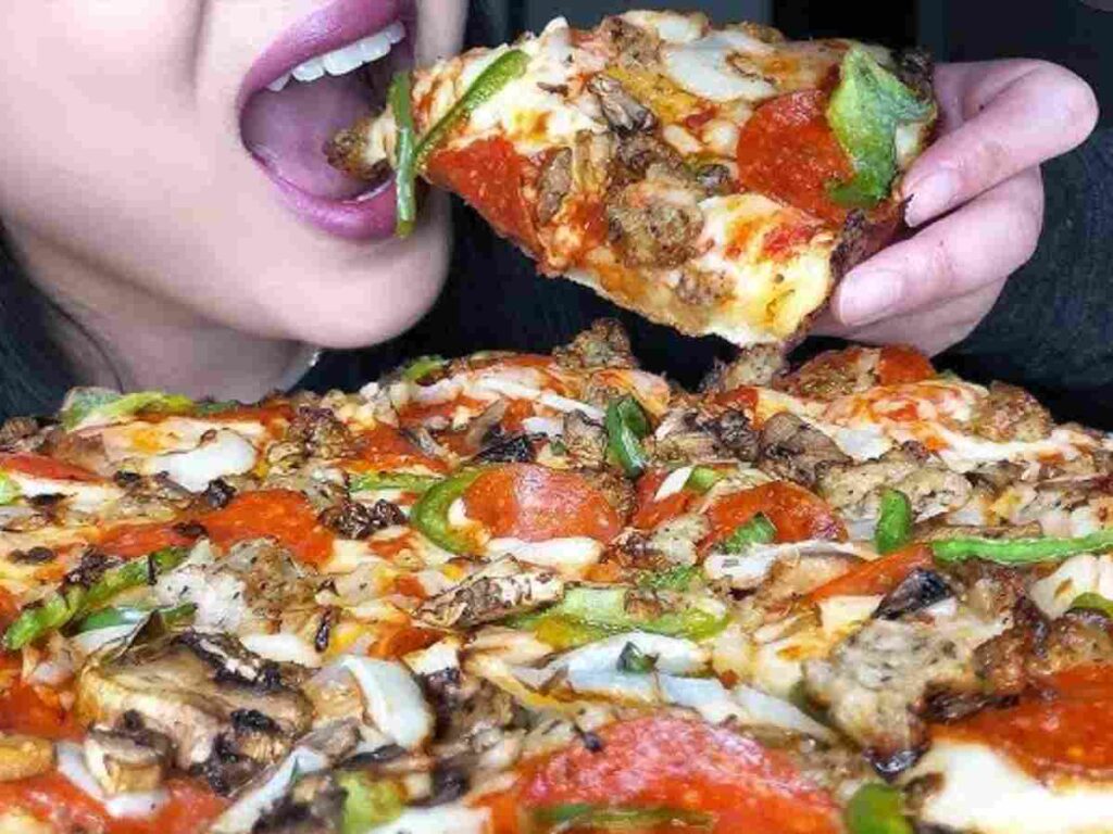 ragazza addenta una pizza super farcita