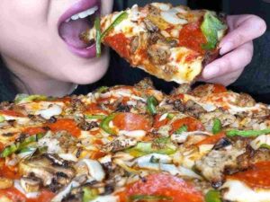 ragazza addenta una pizza super farcita
