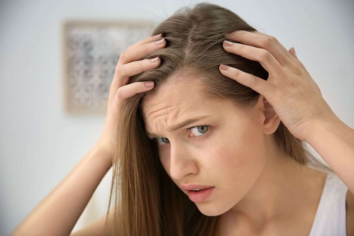Ragazza perplessa controlla capelli allo specchio