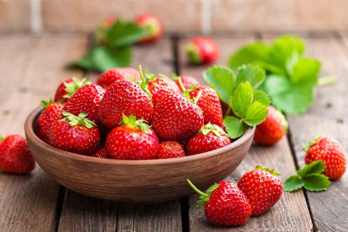 ciotola di legno con dentro fragole rosse e mature