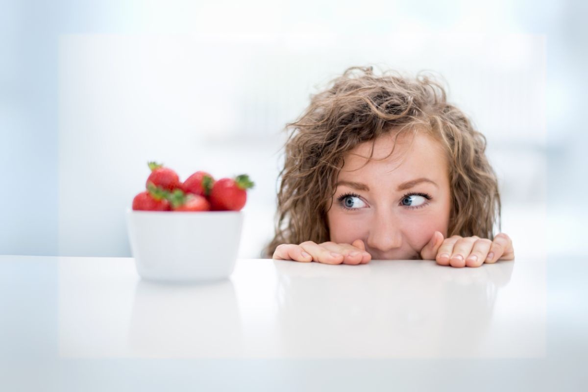 donna che guarda delle fragole sul tavolo