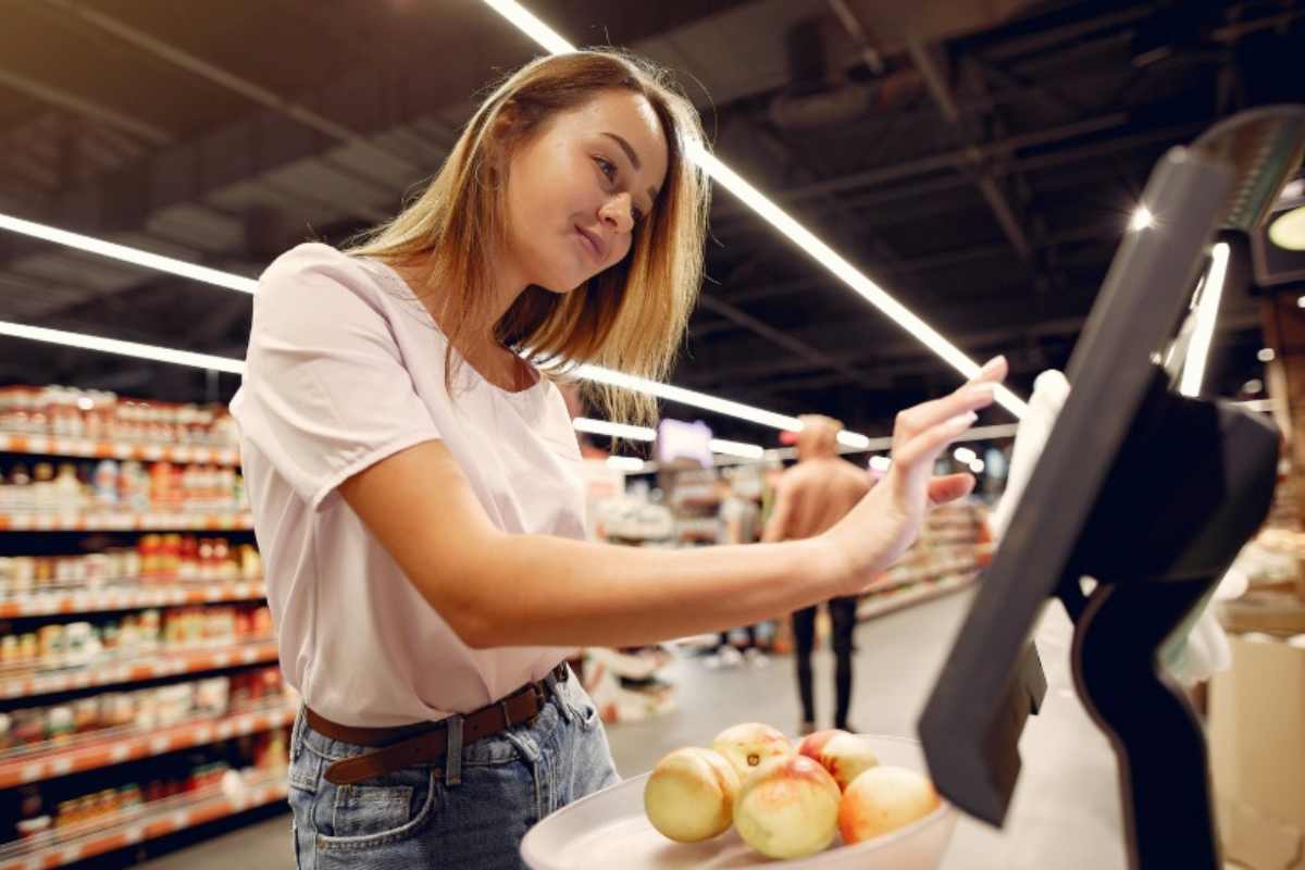 Donna che usa la bilancia elettronica al supermercato