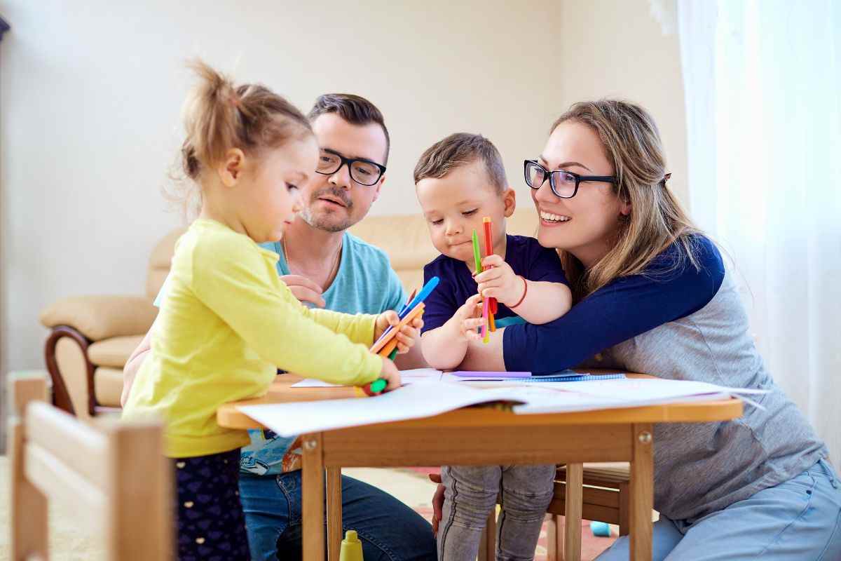 bambini che disegnano e vicino adulti che interagiscono