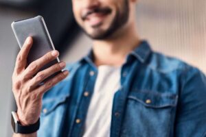 uomo che sorride con telefono in mano