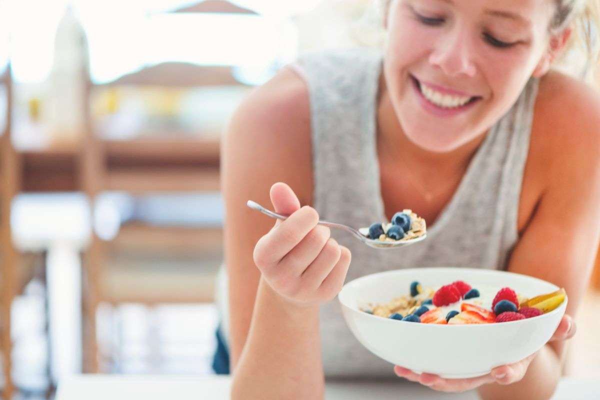 ragazza che mangia yogurt e frutta