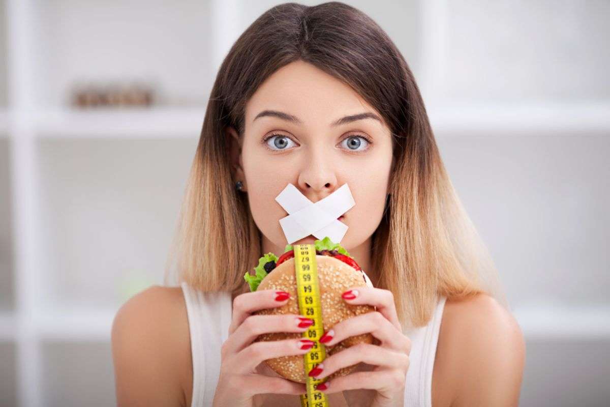 ragazza che si tiene in forma evitando di mangiare un hamburger
