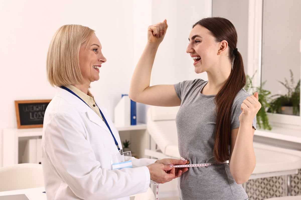 nutrizionista che misura il girovita di una ragazza felice