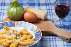 piatto di carbonare con le zucchine, bicchiere di vino rosso e ingredienti