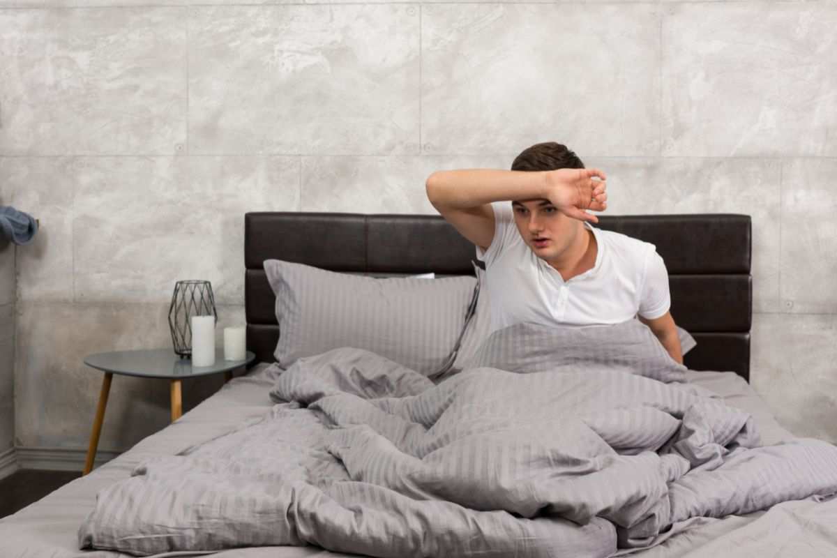 ragazzo che si sveglia sudato nel letto