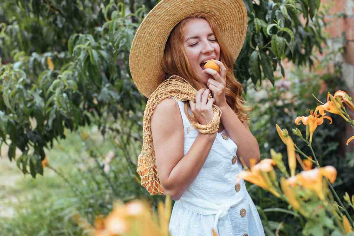 ragazza in campagna che mangia un'albicocca