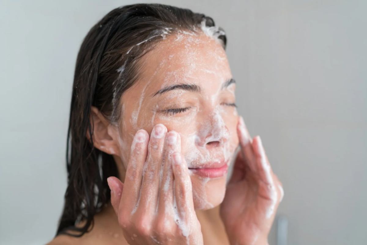 Donna si lava il viso con acqua e detergente