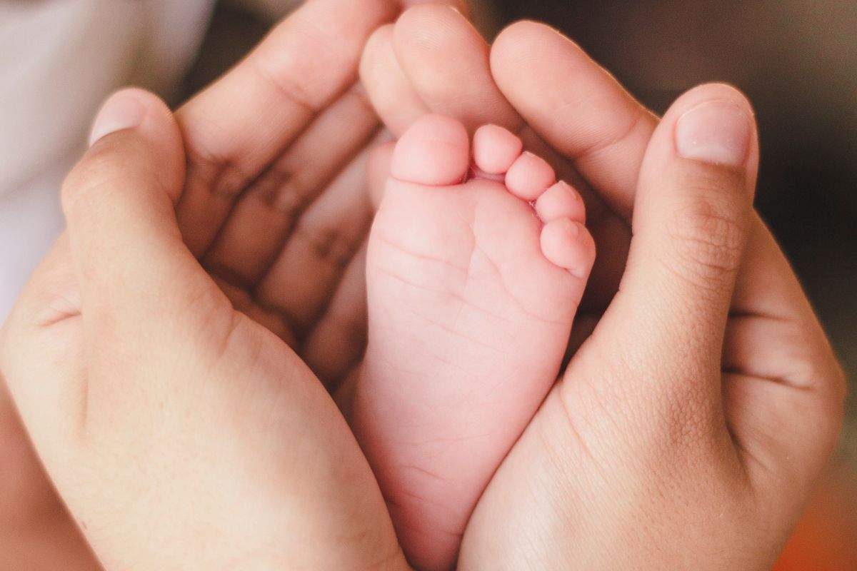 Mamma stringe tra le mani il piede del bimbo