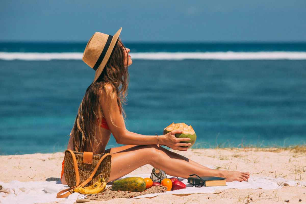 ragazza mangia noce di cocco in spiaggia