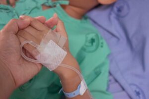 Un bambino tenuto per mano in un letto di ospedale