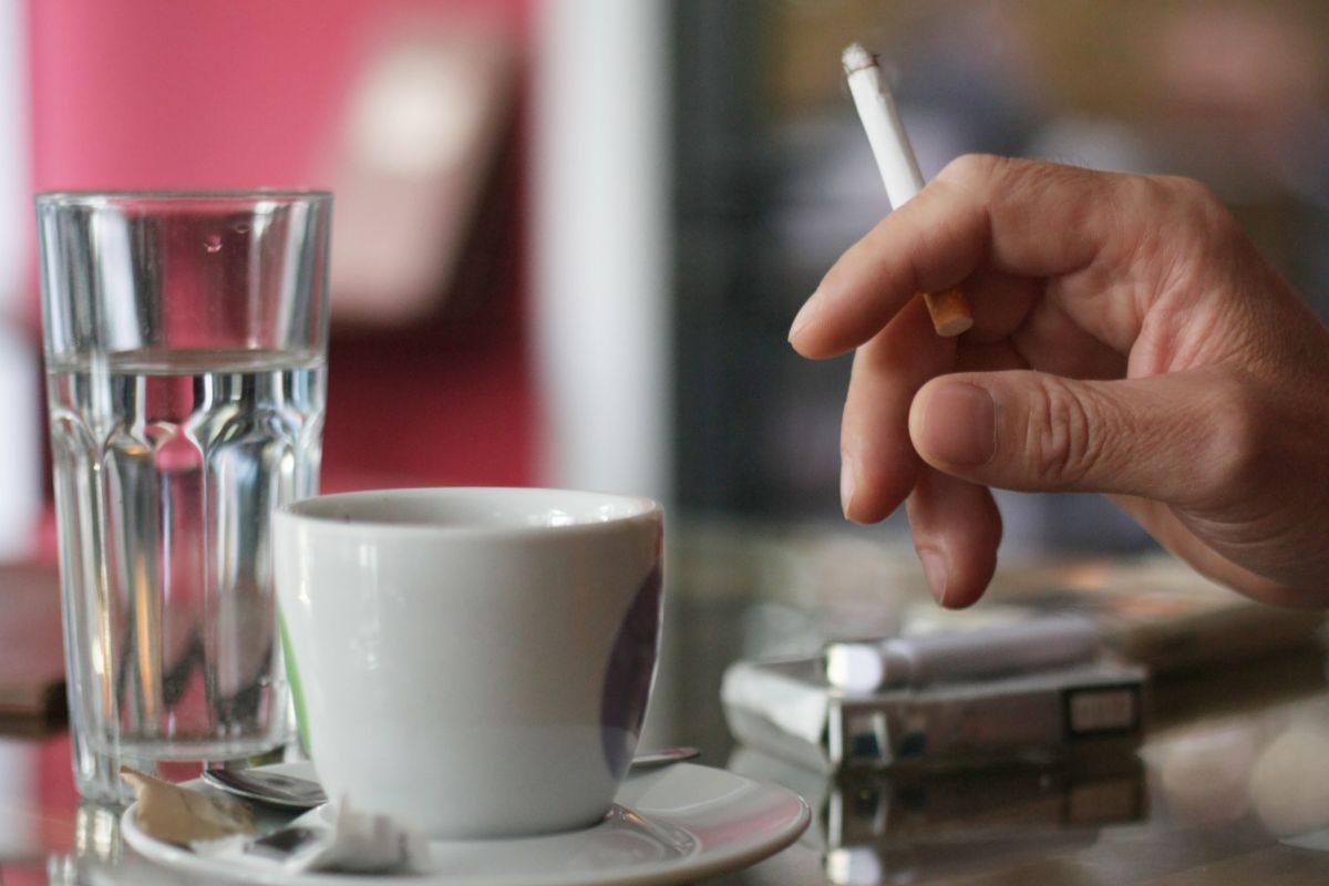 Uomo fuma sigaretta e beve caffè