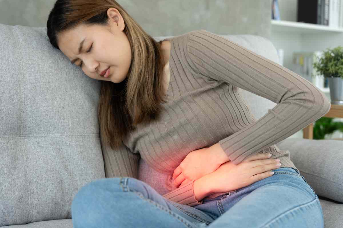 Una donna seduta con mal di stomaco