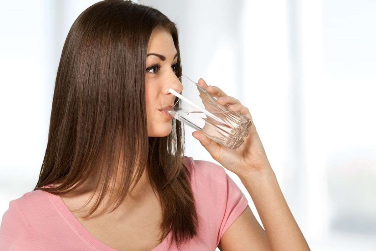 Ragazza si disseta con un bicchiere d'acqua