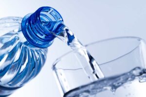 versare acqua in bottiglia in un bicchiere