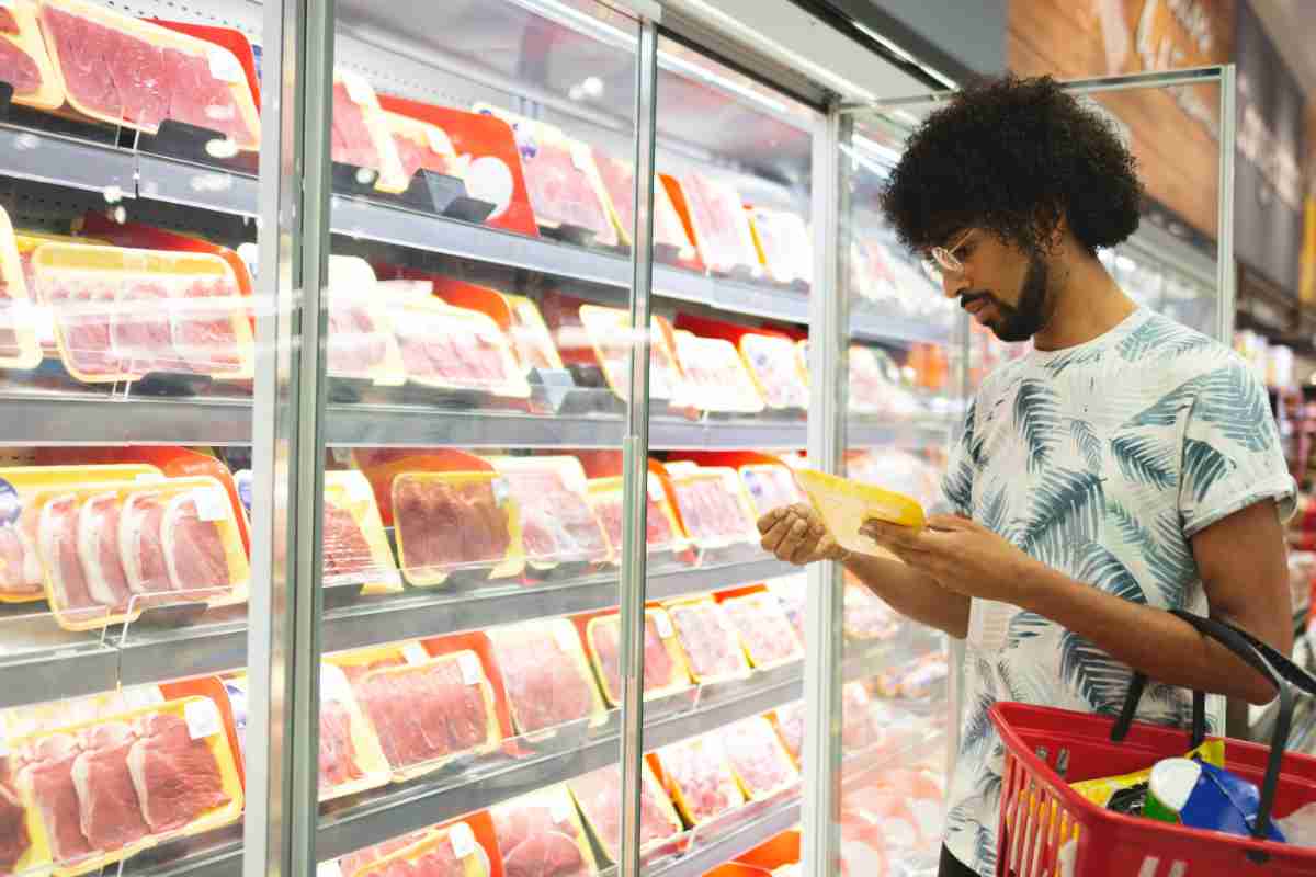 uomo guarda confezione carne al supermercato