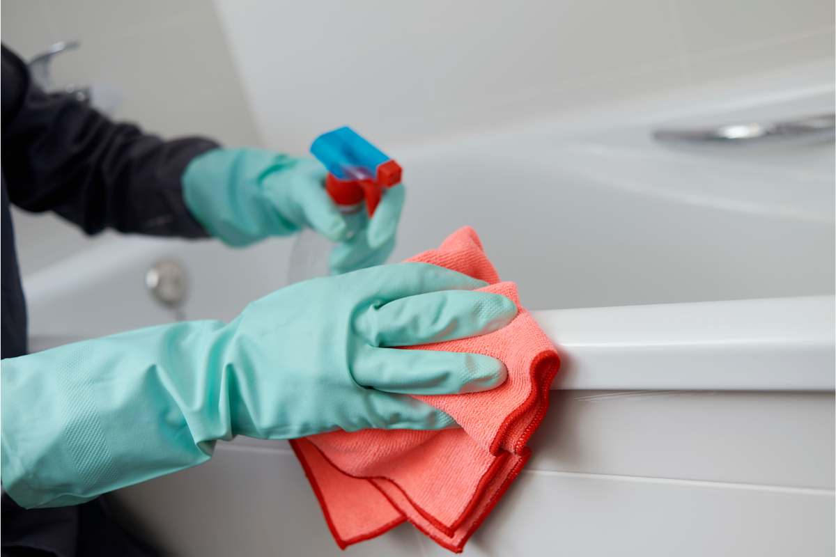 Spugna che pulisce il bordo di una vasca da bagno