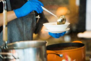 una mano versa la zuppa in una scodella con un mestolo